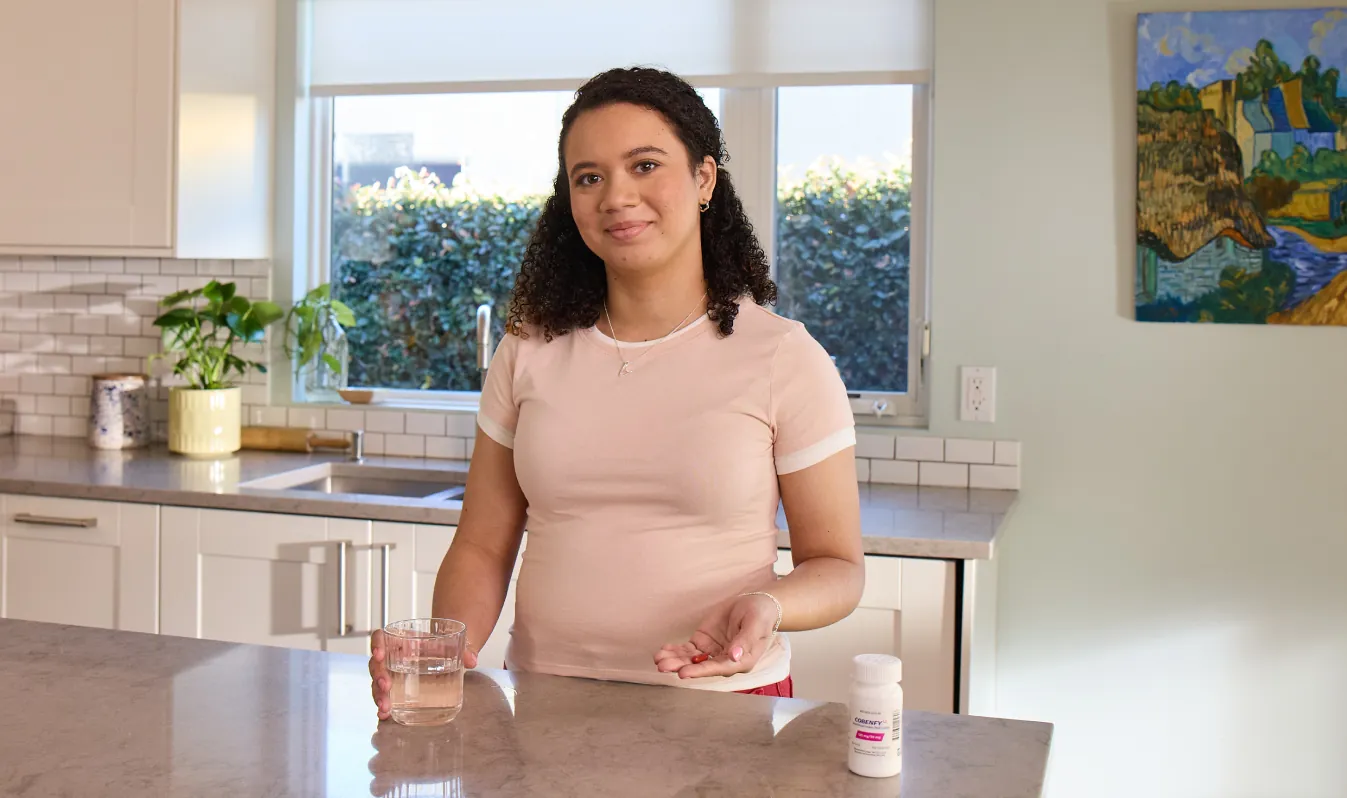Chanel, an actual COBENFY (xanomeline and trospium chloride) patient, in their kitchen about to take a dose of COBENFY. 