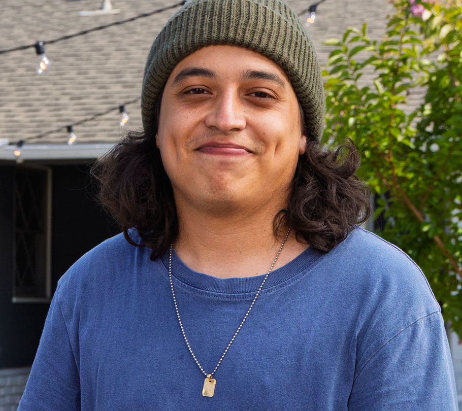 Portrait of Bryan, an actual COBENFY (xanomeline and trospium chloride) patient, wearing an olive green beanie and blue t-shirt